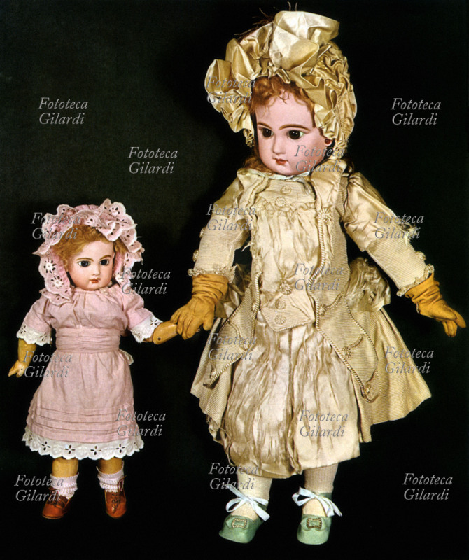 GIOCATTOLI Coppia di bambole. Il corpo è in legno e la testa in porcellana dipinta, i vestiti sono realizzati in panno, cotone e raso, Francia 1880