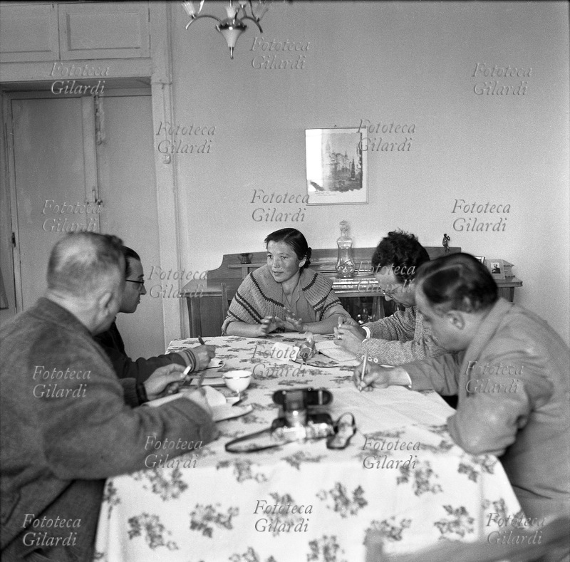 ALBANO DI LUCANIA (PZ) una donna racconta a Ernesto De Martino (1908 - 1965), Emilio Servadio (1904 - 1995), Adam Abruzzi e Mario Pitzurra (1916 - 1998) un episodio di affatturazione. In questo contesto è stata ripresa anche una sequenza di 8 fotogrammi 24x36 che ritraggono solo la donna che parla in primo piano (FSNgilardi_43631.jpg --> FSNgilardi_43638.jpg); sul tavolo una Leica, uno degli apparecchi utilizzati da Gilardi. Il colloquio si svolge in casa del medico del paese, durante l\