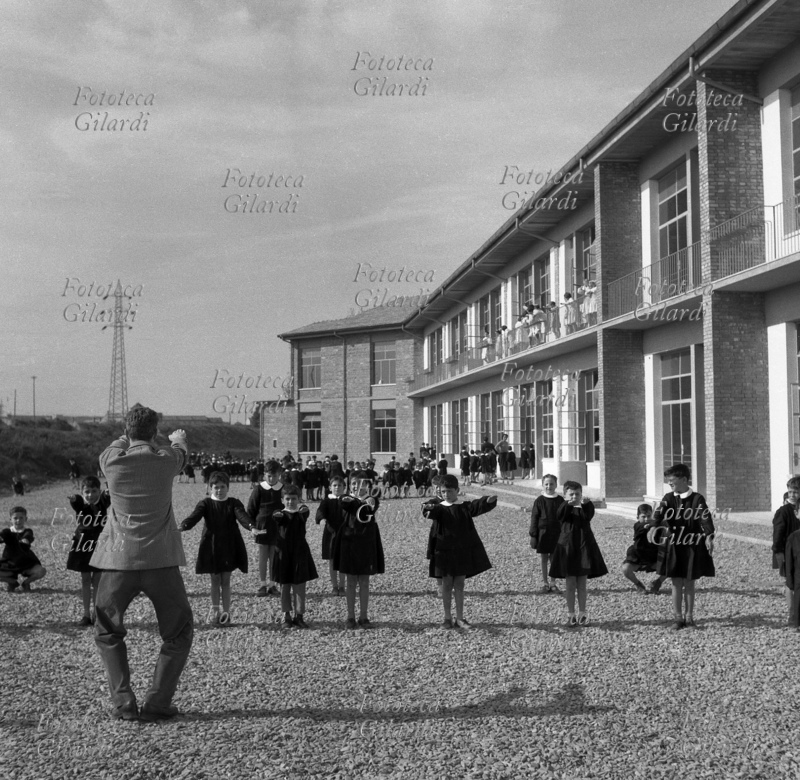 SCUOLA Alunni della scuola elementare fanno ginnastica in cortile con il maestro. Come divisa indossano tutti un grembiule nero. Fotografia di Ando Gilardi (1921 - 2012), #andogilardi, Roma circa 1952.