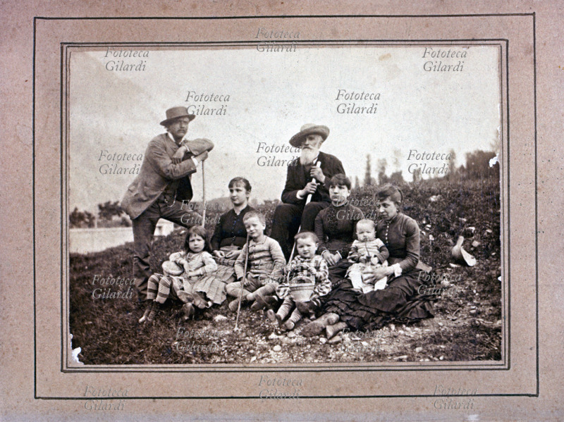 COLLINA fotografia di gruppo nei pressi di un laghetto, forse i nonni con le due figlie, di cui una con il marito e quattro bambini. ripresi durante una breve passeggiata; quasi tutti sono attrezzati con bastoni da passeggio o cestini. Fotografia viraggio seppia, Italia 1895 circa.