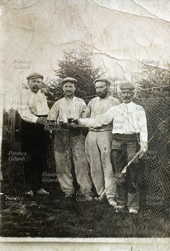 BRINDISI si brinda ad un accordo positivo, sul confine di un terreno delimitato da una rete metallica. Fotografia amatoriale, Italia 1940 circa.