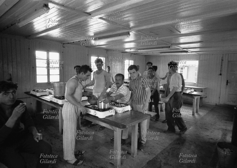 EMIGRAZIONE Italiani nel locale mensa cucinano nostalgicamente spaghetti rigorosamente italiani, conservando così più vicino il ricordo di casa. È un alloggio per soli uomini, e probabilmente è un\