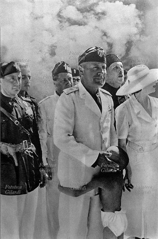 FASCISMO Mussolini (alla sua destra Starace) visita le Colonie estive gratuite per bambini. Nella fotografia sono state aggiunte allo sfondo delle nuvole. Questa fotografia è stata utilizzata anche per un fotomontaggio di propaganda, vedi #8758. Italia 1937