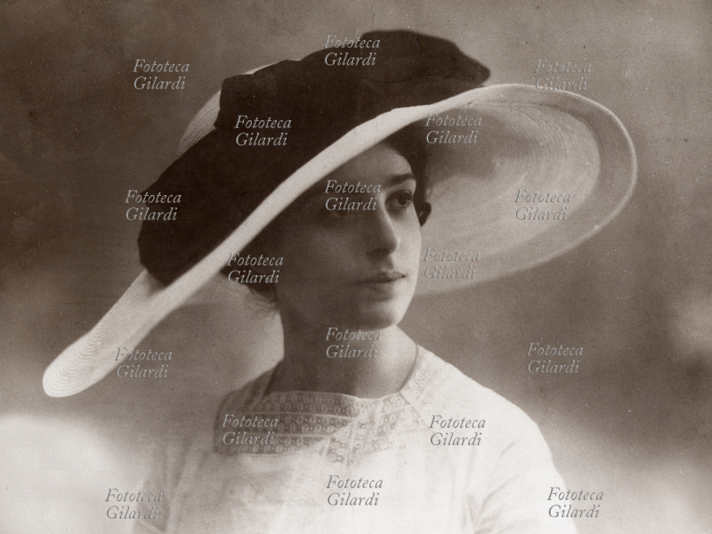 MODA giovane donna con cappello a tesa larga, elegante abito da cerimonia, fotografia 1900 circa