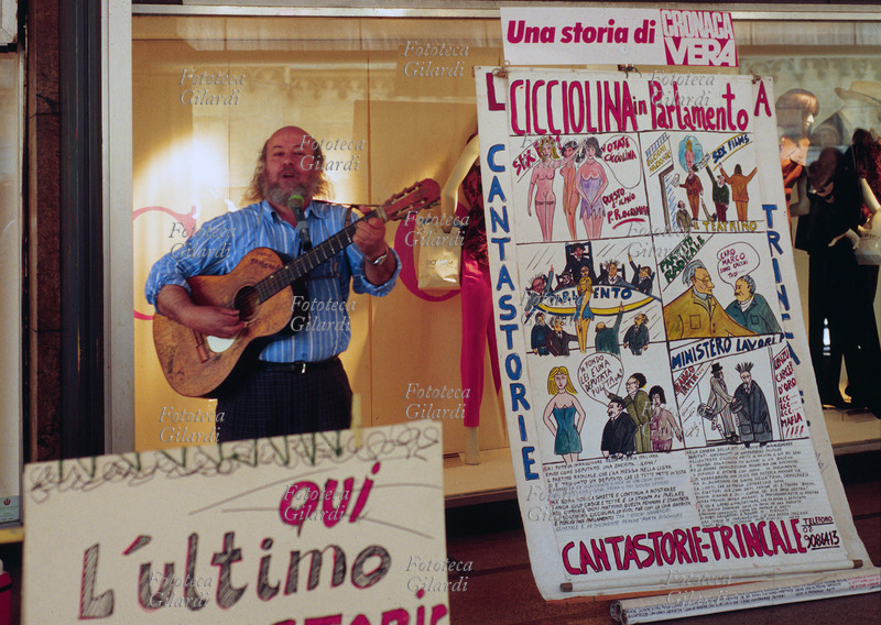 CANTASTORIE Milano, sotto i portici di piazza del Duomo, davanti alle vetrine della Rinascente, si esibisce Franco Trincale (12 settembre 1935), cantastorie italiano (nato in Sicilia) degli anni \