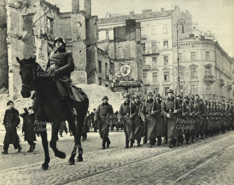 NAZISMO Le truppe tedesche entrano a Varsavia. Un ufficiale a cavallo precede le truppe che marciano con il fucile in spalla. Polonia 1939.