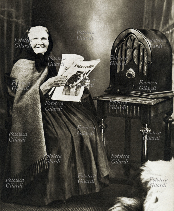 RADIO Le prime radio fanno la loro apparizione nelle famiglie italiane: una simpatica vecchina accanto alla sua nuova radio. Contemporaneamente con la diffusione della radio e delle sue trasmissioni nasce il \