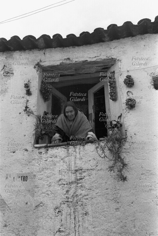 MACIARA del paese incombe affacciata alla finestra intorno alla quale sono appese cipolle ad asciugare. Immagine a documentazione dell\