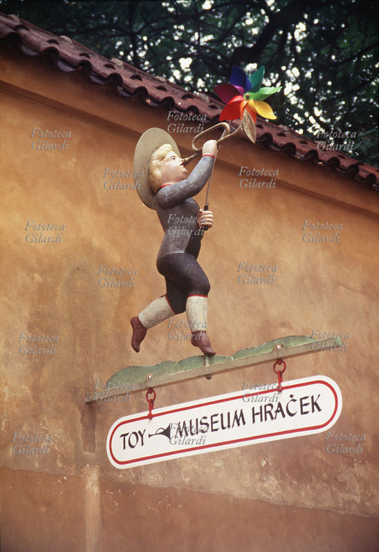 GIOCHI Insegna del Museo dei giocattoli di Praga a Mala Strana. Un bimbo gioca con una girandola colorata e una trombetta. Fotografia di Elena Piccini. Praga, 1995