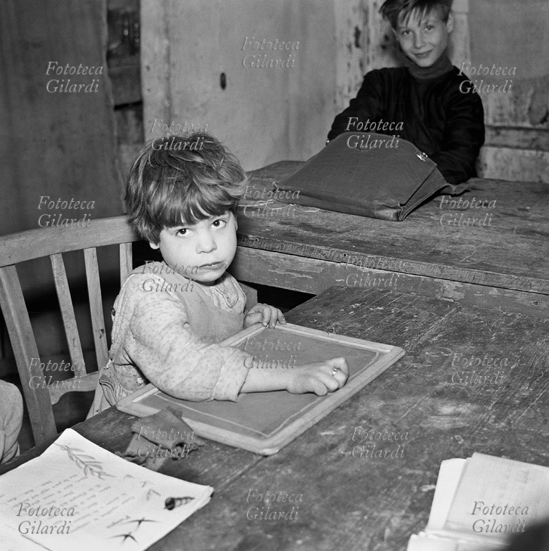 DOPOSCUOLA a cortile Scalilla; bambina disegna sulla lavagnetta al doposcuola dei coniugi Michela e Goffredo Fofi. Fotografia di Ando Gilardi (1921 - 2012) #andogilardi da ampio servizio, Palermo, 1957.