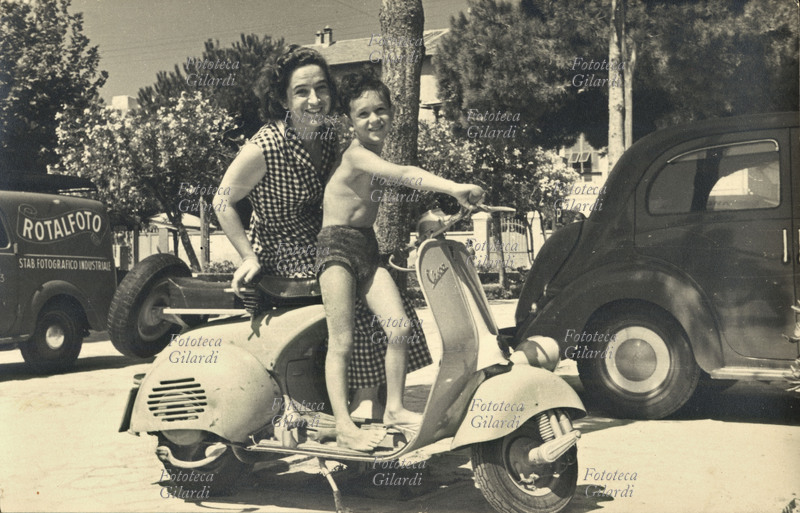 VESPA young mother sprint with son of approximately 7 years, in rests on celebre the motorcycle. Summer, in an Italian bathing locality 1950 approximately.
