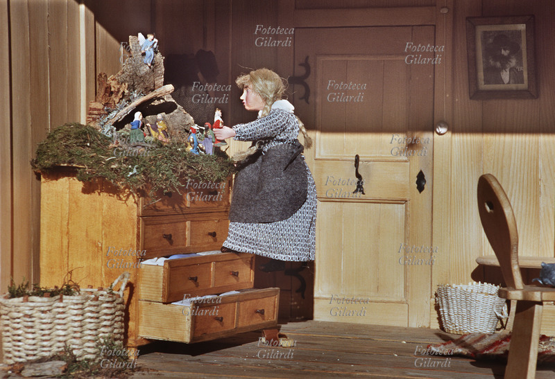PRESEPIO Ricostruzione di una abitazione tradizionale di montagna con la famiglia riunita per le feste natalizie. La bimba mette le statuine nel presepio salendo sui cassetti della cassettiera come su una scaletta. Il presepio è stato esposto durante la manifestazione "10 anni dei \