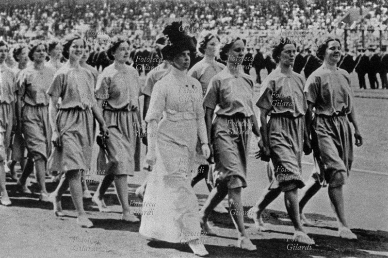 OLIMPIADI di Stoccolma. La comparsa delle prime atlete alle competizioni internazionali. Fino a questo momento le donne avevano partecipato solo alle gare di tennis e a quelle di cricket. Qui sfila in parata la squadra femminile britannica di atletica leggera. Fotografia, Stoccolma, 1912.