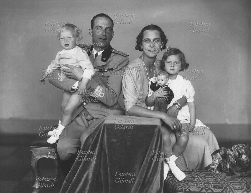 UMBERTO di Savoia (futuro Umberto II, 15 settembre 1904 – 18 marzo 1983), principe di Piemonte, con la consorte Maria Josè del Belgio (4 agosto 1906 – 27 gennaio 2001) e i figli Vittorio Emanuele (12 febbraio 1937 – 3 febbraio 2024), Principe di Napoli, e Maria Pia (24 settembre 1934), Altezza Reale. Ritratto fotografico eseguito da Ghitta Carell (20 settembre 1899 – 18 gennaio 1972), fotografa ungherese naturalizzata italiana, ritrattista ufficiale dei reali d\
