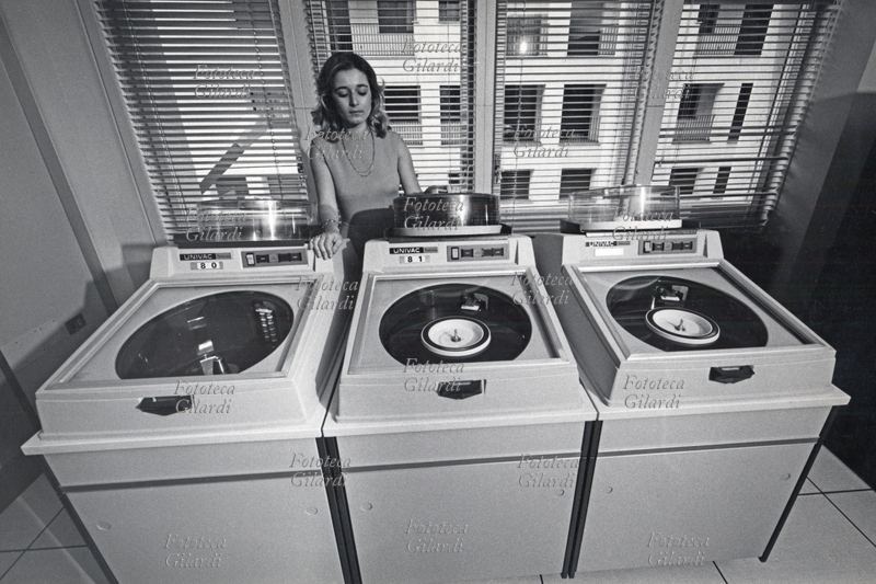SETTORE TERZIARIO Impiegata della Banca Alto Milanese al lavoro su calcolatori elettronici UNIVAC. Le memorie su enormi dischi magnetici occupano intere stanze. Fotografia di Ando Gilardi (1921 - 2012) #andogilardi, Busto Arsizio, 1970 circa.