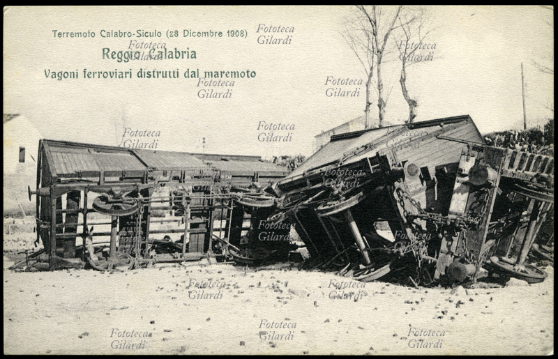 TERREMOTO Calabro-Siculo del 1908. Reggio Calabria, vagoni ferroviari distrutti dal maremoto, deragliati e ridotti a rottami contorti. Il terribile sisma di magnitudo 7,2 ha contato fra le 90.000 e le 120.000 vittime in tutta la zona colpita. Cartolina postale da una serie edita dalla Croce Rossa a sottoscrizione per i terremotati, sistema mediatico pionieristico per la raccolta dei fondi a favore delle vittime di catastrofe naturale, che nell\