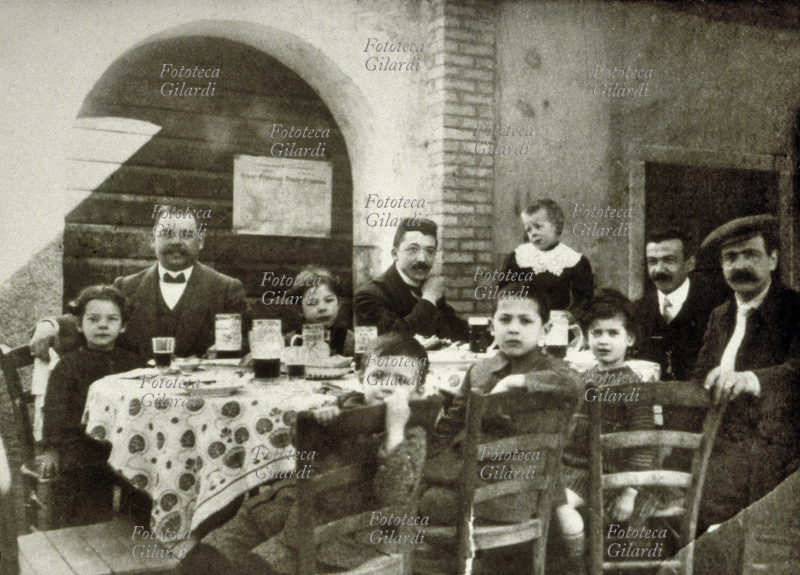 FAMIGLIA Pranzo in occasione di una festività, a tavola padri e zii con bambini. Fotografia dei primi anni del XX secolo