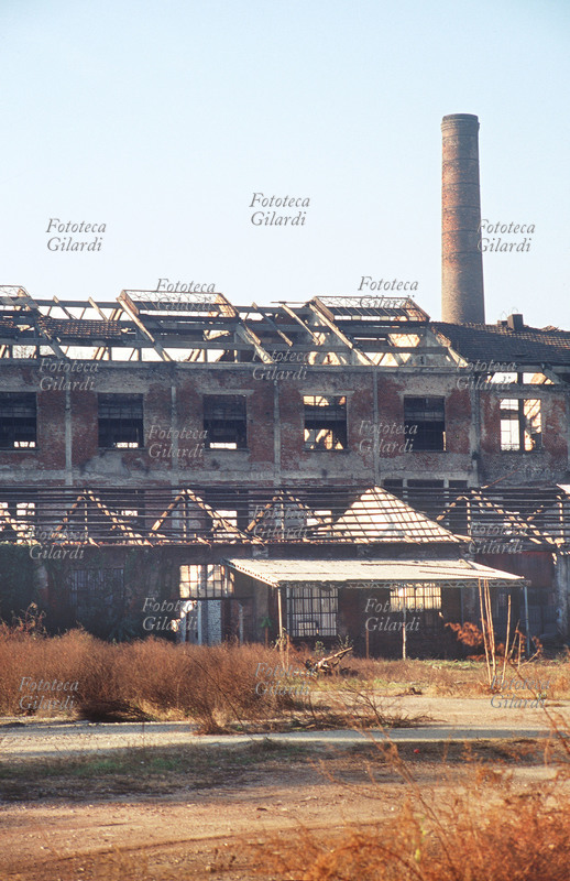 STORIA INDUSTRIA Area industriale dismessa. Veduta di un edificio fatiscente dietro al quale si vede una ciminiera in mattoni. Fotografia di Elena Piccini, Milano, zona Bovisa 2001.