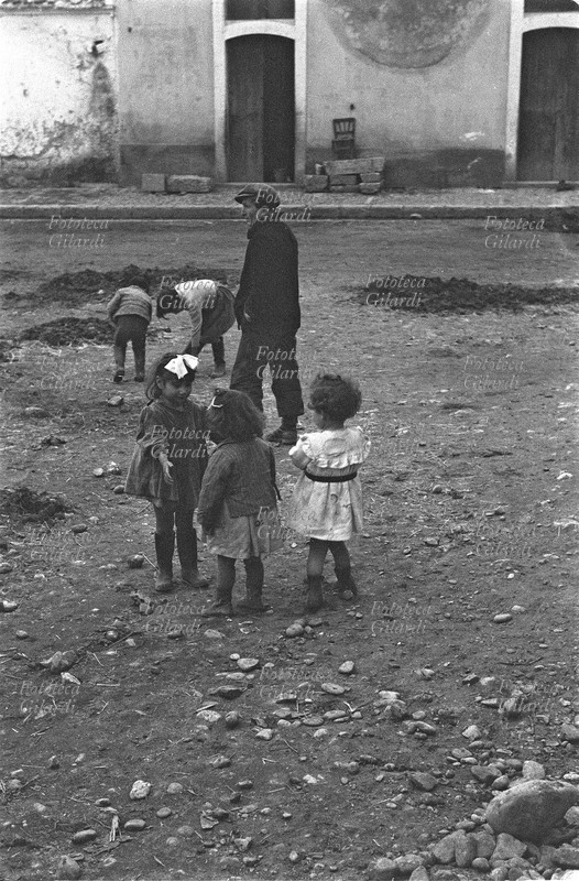 ITALIA Venosa, bambini nella strada coperta di fango. Fotografia di Ando Gilardi (1921-2012) #andogilardi, parte di un ampio servizio realizzato per \
