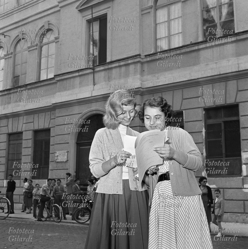 SCUOLA A fine anno scolastico due studentesse del Liceo Ginnasio Torquato Tasso leggono soddisfatte i loro risultati in pagella, davanti al portone del Liceo Scientifico Augusto Righi che si trova nello stesso edificio della loro scuola, ma con l\