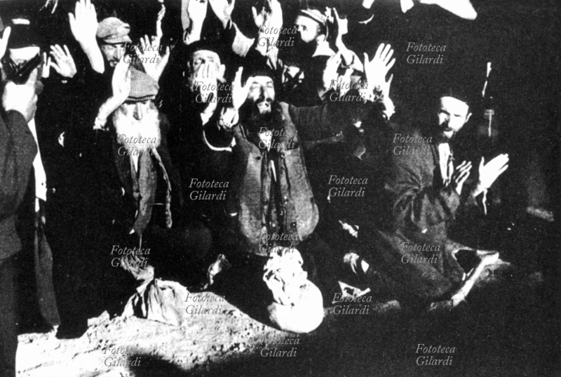 ANTISEMITISMO un gruppo di Ebrei, giovani e anziani, sorpresi nel loro nascondiglio, vengono costretti a cantare una canzone tradizionale ebraica, in ginocchio, a mani alzate e sotto la minaccia di una pistola. Grab, Polonia, 1939-45.