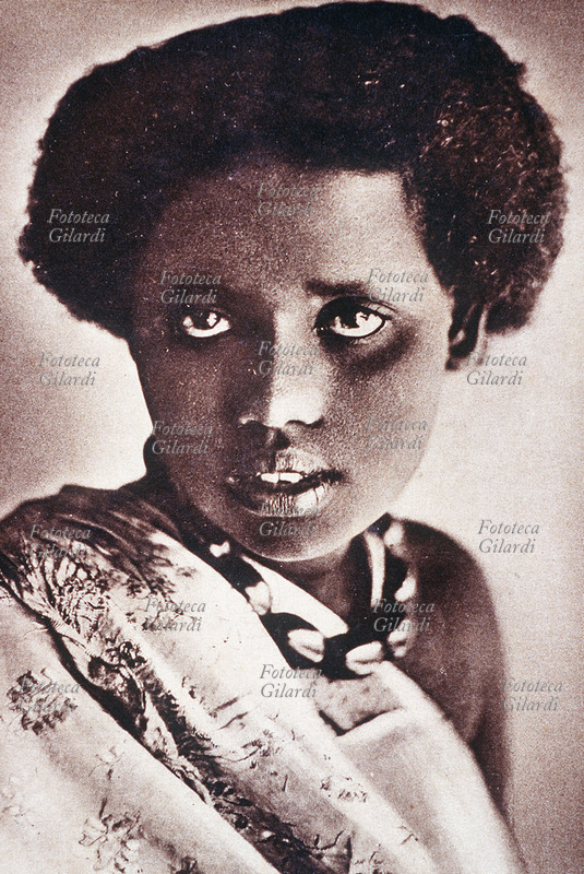 COLONIALISMO A.O.I./Somalia. Ragazza somala. Ritratto fotografico a mezzo busto, frontale. Cartolina litografica, Mogadiscio s.d.
