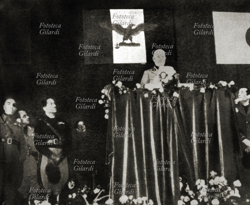 Benito MUSSOLINI (1883-1945) parla al Teatro Lirico di Milano dove si è tenuta una manifestazione fascista. Sotto la palco ascoltano il discorso A. Pavolini con Francesco Barracu sottosegretario alla Presidenza del Consiglio della Repubblica di Salò, R.S.I. . (Fotografia di scarsa qualità, ma rara) Milano 1944