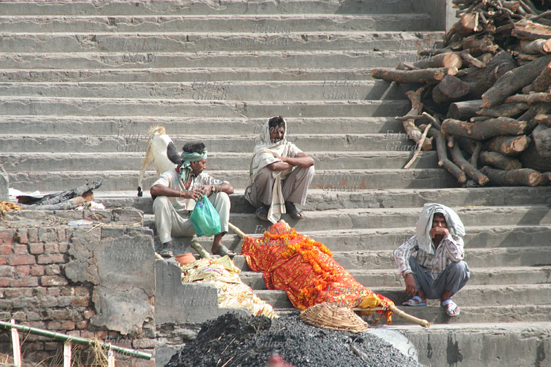 INDIA Il Manikarnika ghat lungo il Gange. I familiari aspettano per la cremazione del defunto. Il colore della stoffa che avvolge i corpi è diverso per donne (rosso), uomini (bianco) e anziani: in questo caso l\