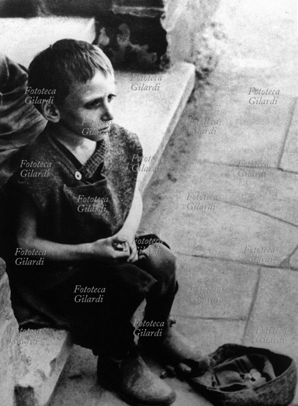 II G.M. POLONIA 1942 Un bambino mendicante nel ghetto di Varsavia, seduto sul marciapiede. Polonia, 1942.