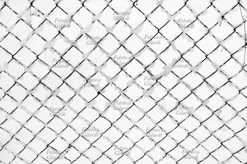 PRIGIONE DI NEVE una rete di recinzione innevata per dare il senso dei disagi e gravi impedimenti causati talvolta dalla neve. Fotografia di Patrizia Piccini, Ponzone (AL) febbraio 2010