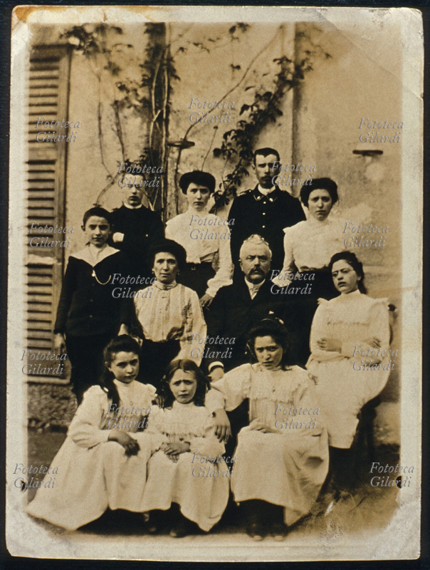 FAMIGLIA numerosa, fotogruppo composto dai genitori, seduti al centro, con i nove figli. Fotografia di anonimo, eseguita in esterno. Italia, 1895 circa.