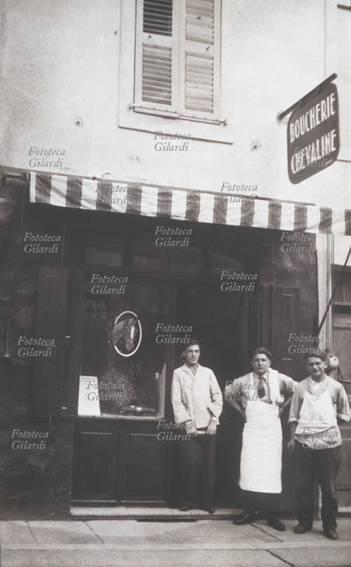 EMIGRAZIONE Macellaio posa sulla porta del negozio con i due garzoni. I tre sono italiani provenienti da un paese della bassa mantovana, emigrati in Francia. La fotografia è stata realizzata per far vedere l\