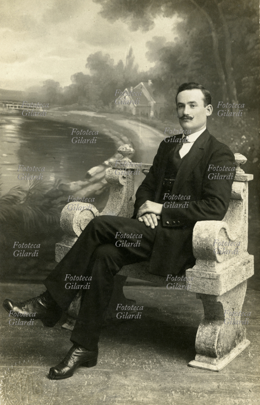 FASHION An elegant gentleman in a dark suit poses seated on a stone bench; the painted backdrop simulates a park, a photographic studio setup. It is likely the portrait an Italian emigrant sent to his family in Italy, his country of origin. Photograph: Valls, Buenos Aires, circa 1920.