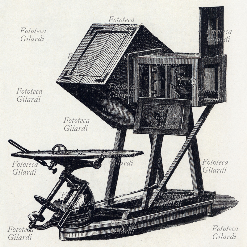 STORIA DELLA FOTOGRAFIA Ingranditore solare. Il piatto orizzontale è uno specchio che raccoglie e convoglia la luce solare verso un secondo specchio posto nella cassa, che illumina un piccolo negativo proiettandolo amplificato su un supporto cartaceo o di vetro, nel caso si voglia ottenere una diapositiva. Il piatto è tenuto costantemente orientato sotto il sole grazie ad un movimento ad orologeria. Lo strumento veniva usato per produrre diapositive scientifiche, 1864.