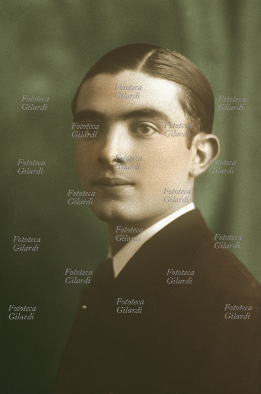 RITRATTO maschile singolo. Ragazzo di circa quindici anni ritratto in tenuta molto elegante e pettinato con la brillantina. Fotografia colorata R. Prezioso, Acqui Terme (AL), 1936 circa.