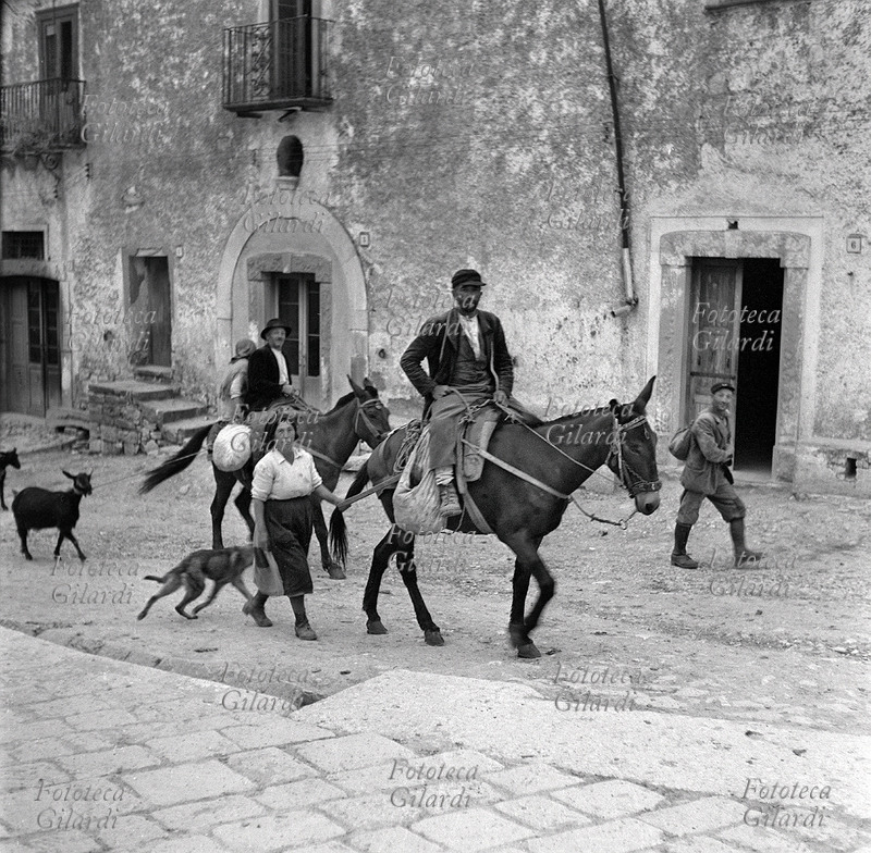 AGRICOLTURA due coppie di contadini tornano dai campi e arrivano in paese. In primo piano l\