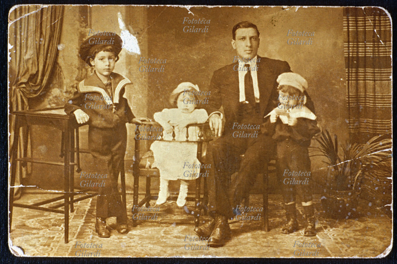 FAMIGLIA padre con i tre figlioletti: tutti si appoggiano con diversi espedienti, escogitati per sembrare naturali, per sopportare l\