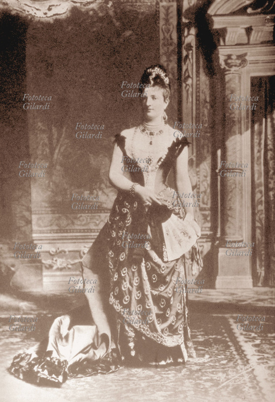 MARGHERITA di Savoia, ritratto fotografico della regina a figura intera, che indossa un sontuoso vestito e ricchi gioielli. Italia, 1880 c.