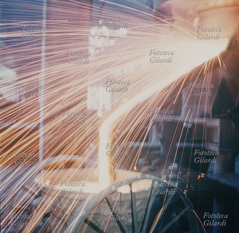 INDUSTRIA Primo piano di una colata di ghisa; una infinità di scintille escono dalla bocca del forno insieme alla colata, tracciando nell\