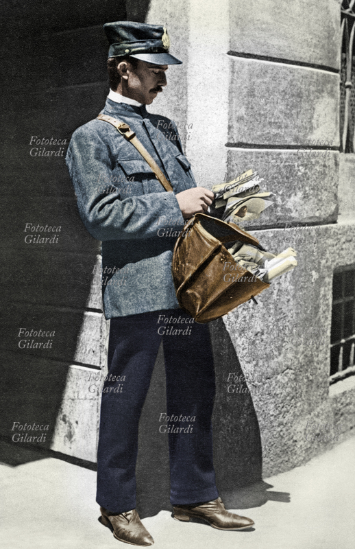 POSTA il postino in uniforme osserva un mazzo di lettere della sua tipica sacca di cuoio; forse le sta mettendo in ordine secondo il giro della consegna. Italia, 1925 circa