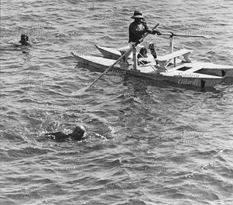Benito MUSSOLINI (1883-1945) al mare nuota scortato da un bagnino che lo segue in \