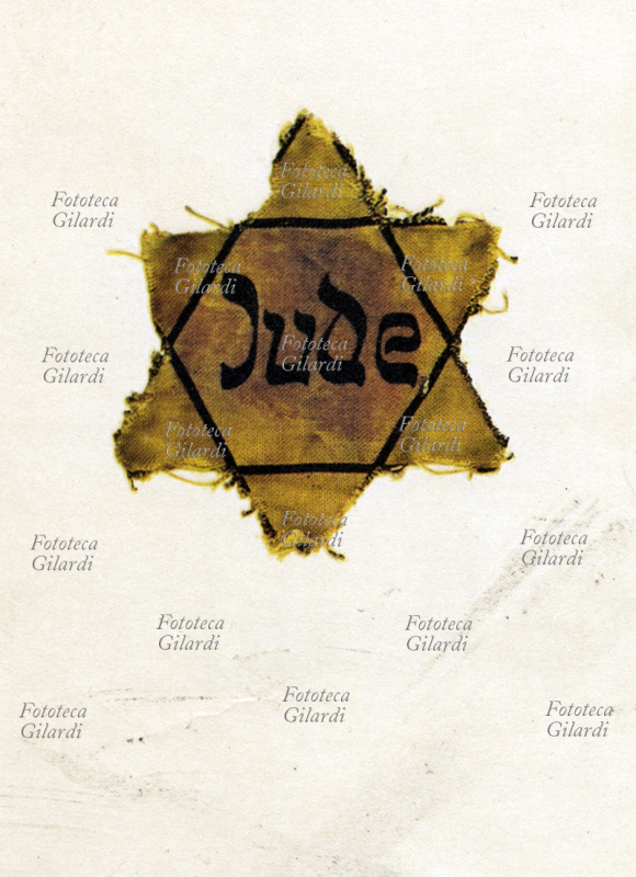 SHOAH Fotografia di una stella gialla, distintivo che gli ebrei dovevano portare sulle divise nei campi di concentramento e nei ghetti. Questo esemplare è del superstite Alfred Kantor (1923-2003), artista ebreo cecoslovacco sopravvissuto a Terezin, Auschwitz, e Schwarzheide; la stella è conservata in una pagina del diario da lui stesso illustrato in cui, a rischio di essere scoperto, ha voluto raccontare la vita quotidiana nei campi di concentramento e sterminio, lasciando una traccia fondamentale dei tragici avvenimenti del 1944-1945.