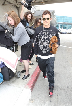 Orlando Bloom returned to Los Angeles carrying his puppy and signing autographs on his way to his waiting vehicle.
